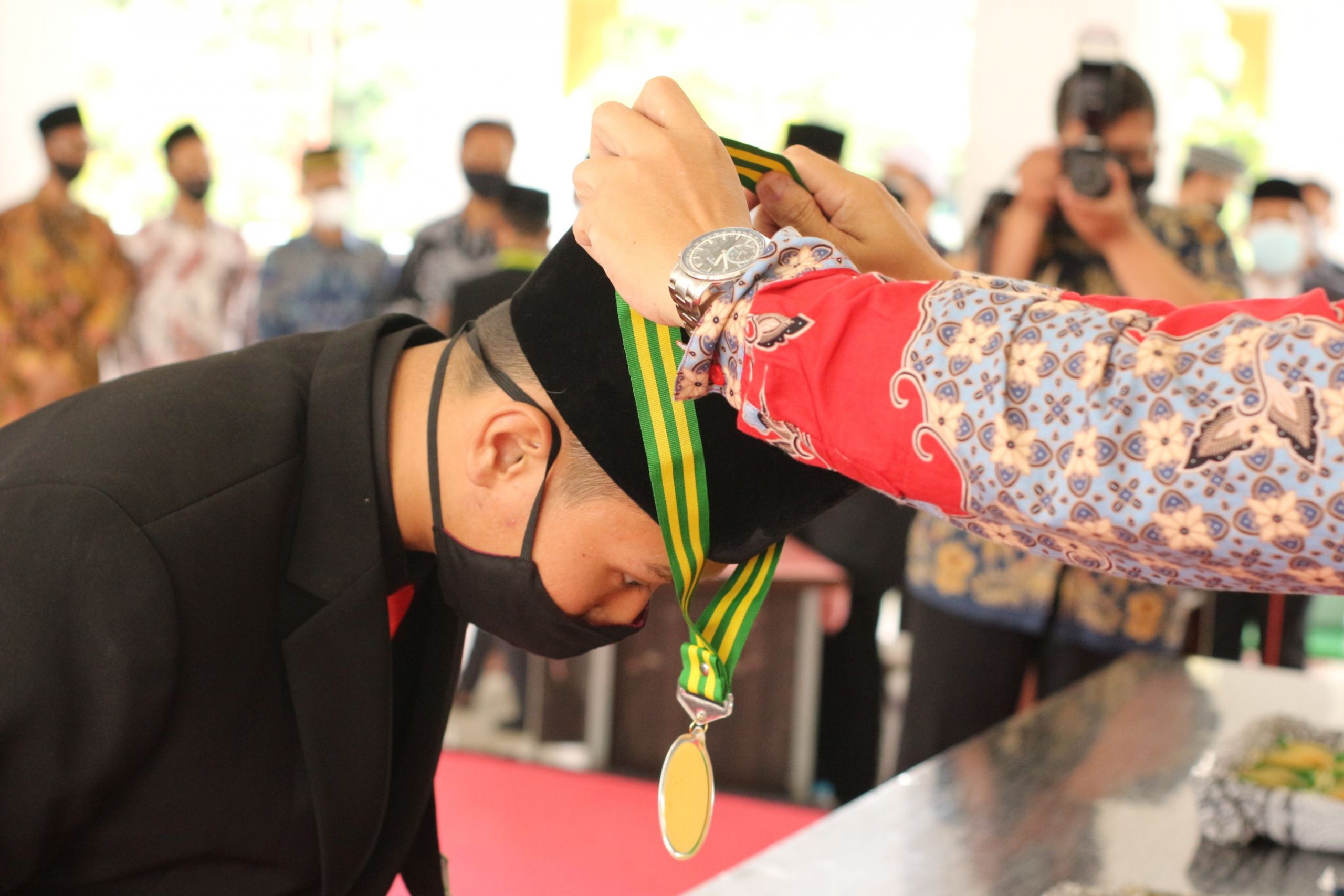 A young man receives a medal during a graduation ceremony.